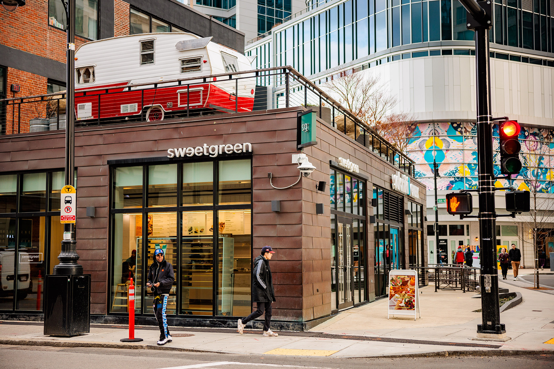 A city street corner in Boston showing a building that houses the market Sweetgreen.