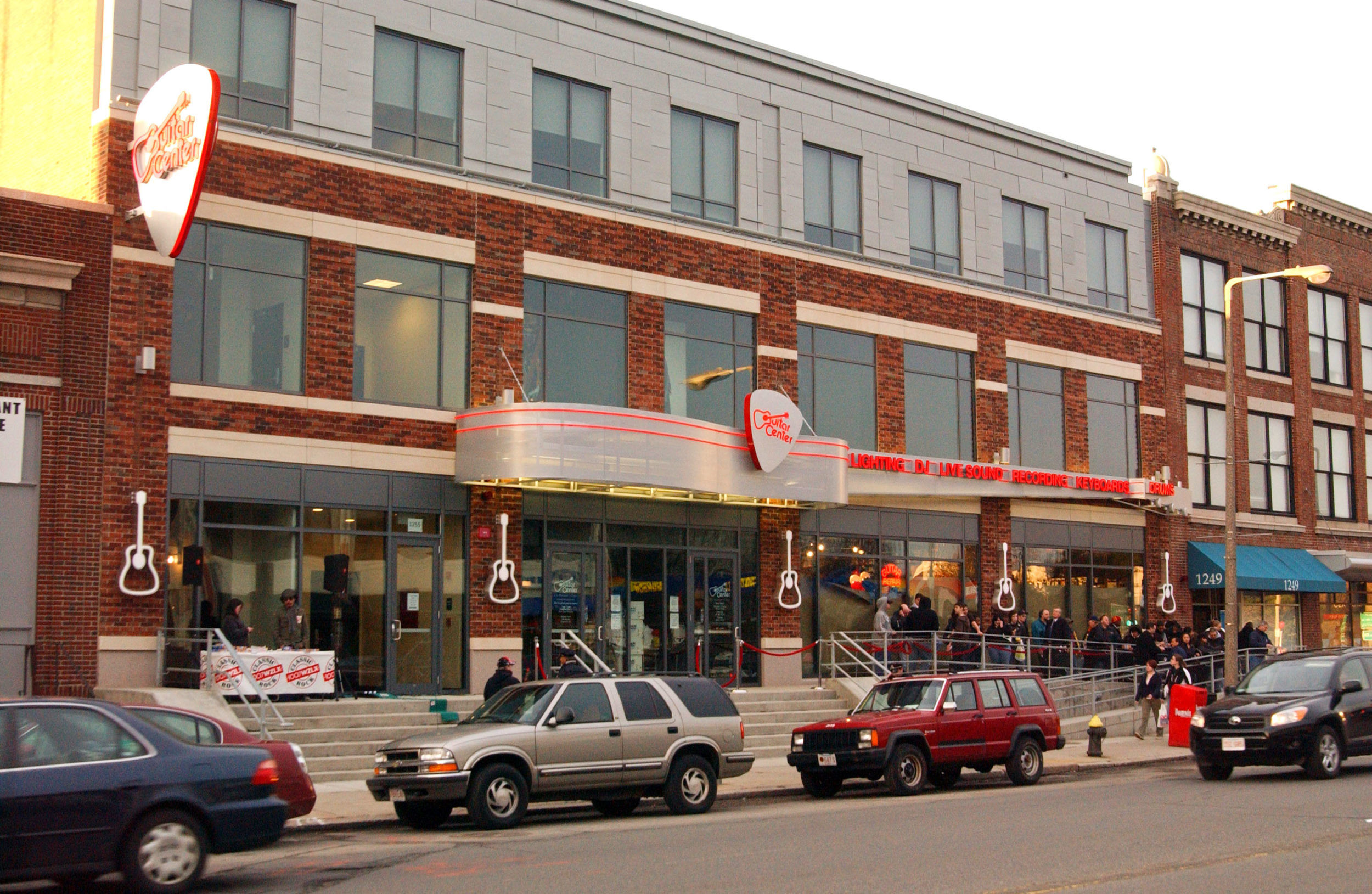 People line up outside of the Guitar Center, a music store in The Fenway, waiting for it to open.